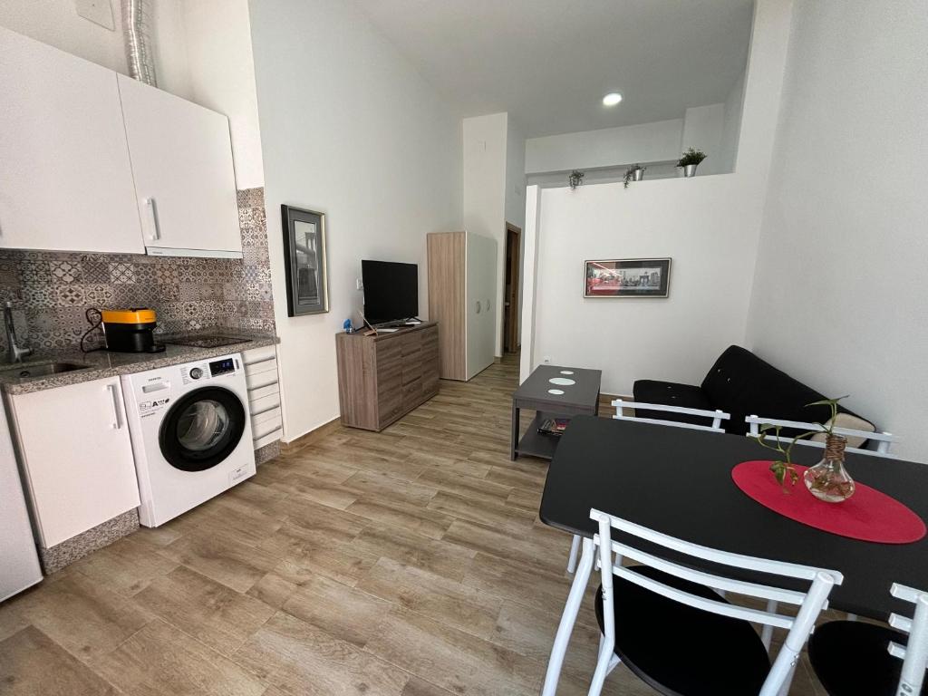 uma cozinha e sala de estar com uma mesa e uma máquina de lavar roupa em Apartamento Cruz Roja A em Sevilha