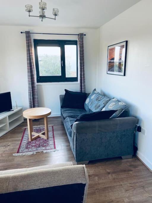 a living room with a blue couch and a table at Bally, 2 Bed Flat, by Grays Station in Stifford