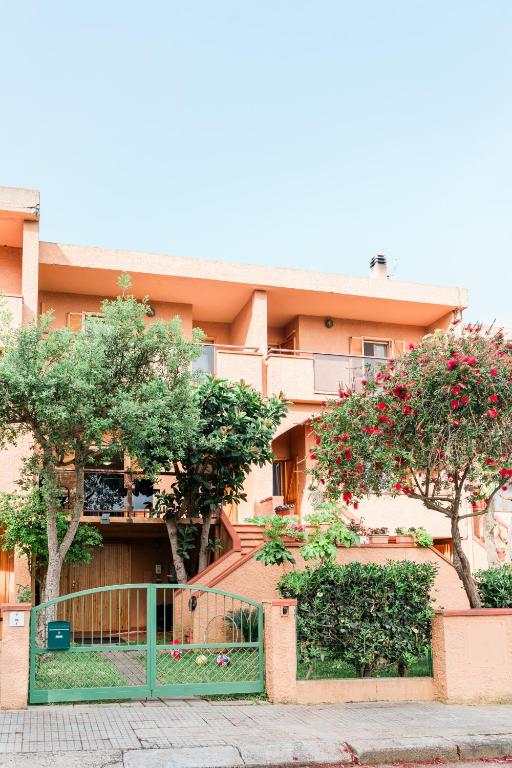 a building with trees and a fence in front of it at Stella Maris Holidays in Porto Conte