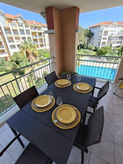 une table noire avec des assiettes et des chaises sur un balcon dans l'établissement Les Calanques d'Azur, à Saint-Aygulf