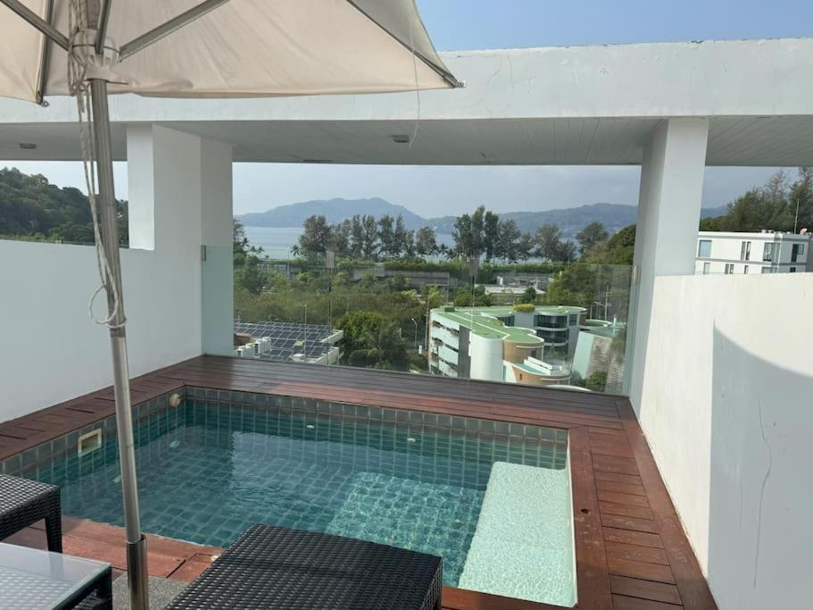 a swimming pool on a balcony with an umbrella at Sea view studio with private terrace & pool in Patong Beach