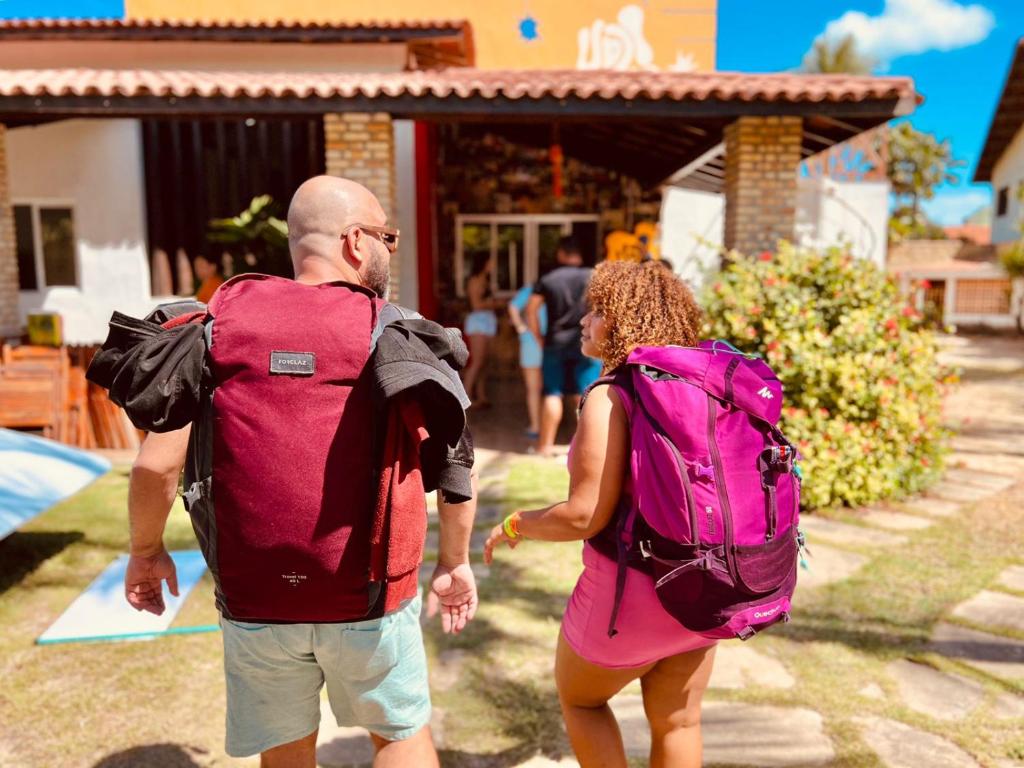 un hombre y una mujer caminando delante de una casa en UP2! HostelBAR CUMBUCO, en Cumbuco