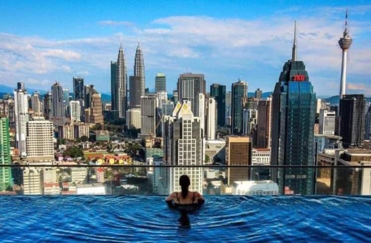 a person in a infinity pool with a city skyline at KLCC View by Regalia Dorms in Kuala Lumpur