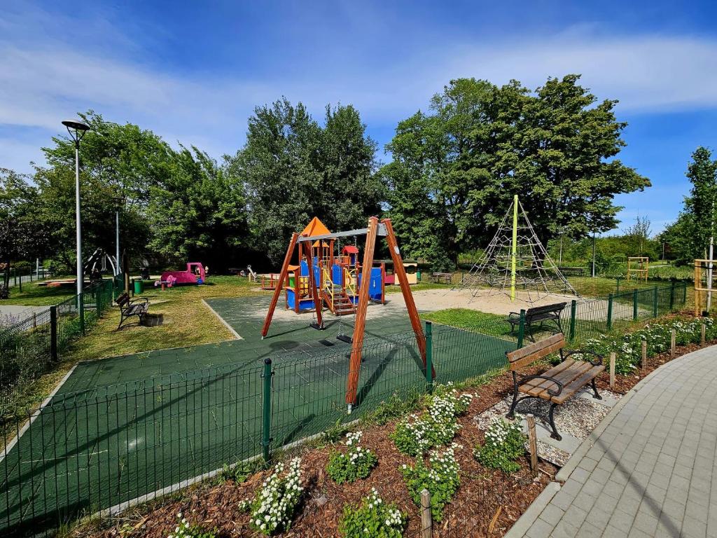 einen Park mit Spielplatz mit Rutsche und Bank in der Unterkunft Cottage Studio in Borzęcin Duży