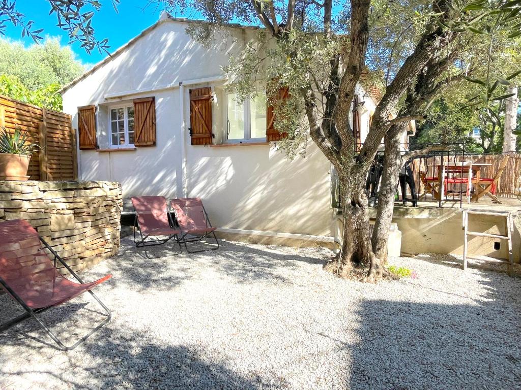 una casa blanca con sillas y un árbol en Maison au calme avec jardin et parking, proche de tout !, en La Ciotat