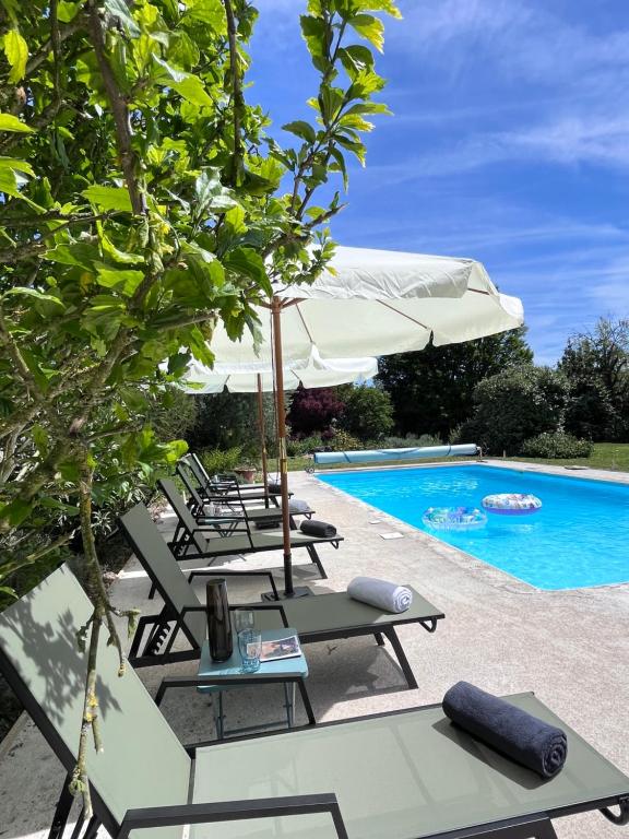 un grupo de sillas y sombrillas junto a una piscina en Le Clos Gabrielle en Châtellerault