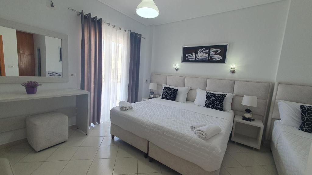 Habitación blanca con cama y espejo en Hotel Ceko, en Sarandë