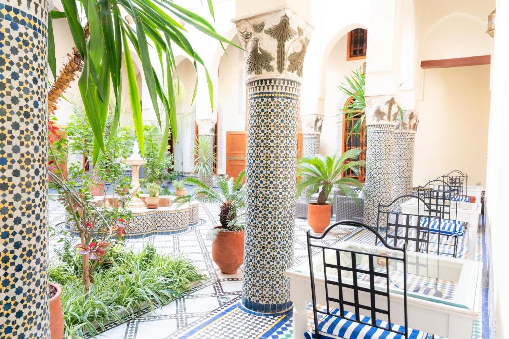 a lobby with columns with plants and chairs at Riad Al Ansari in Fez