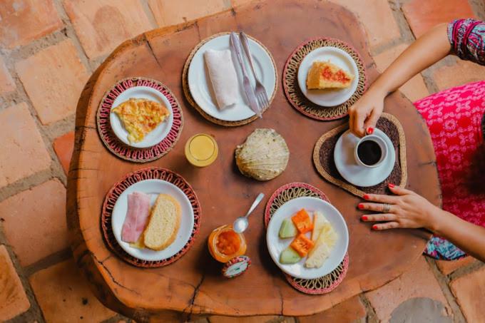 una mesa con platos de comida y una taza de café en Rancho do Buna en Atins