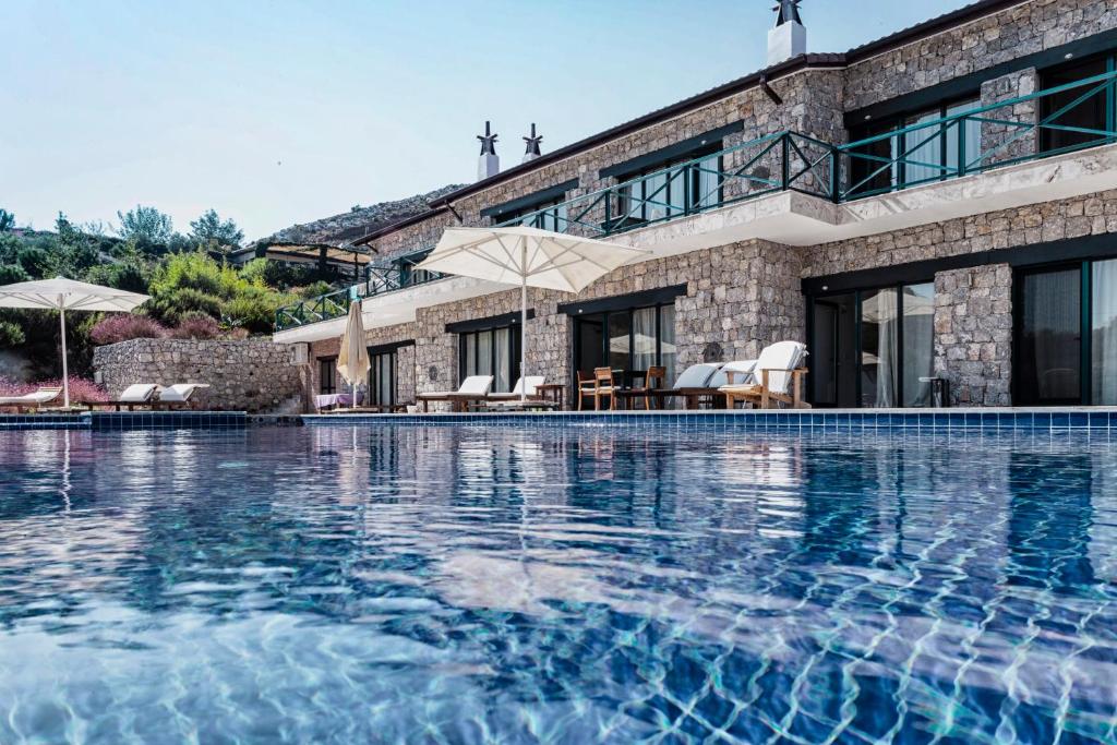 a large swimming pool in front of a house at Kekik Otel Selimiye in Selimiye