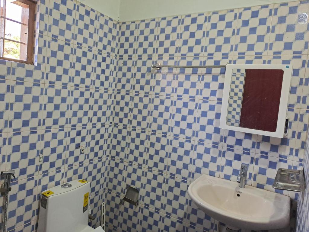 a blue and white tiled bathroom with a sink and a toilet at NATURE FAMILY HOMESTAY in Munnar