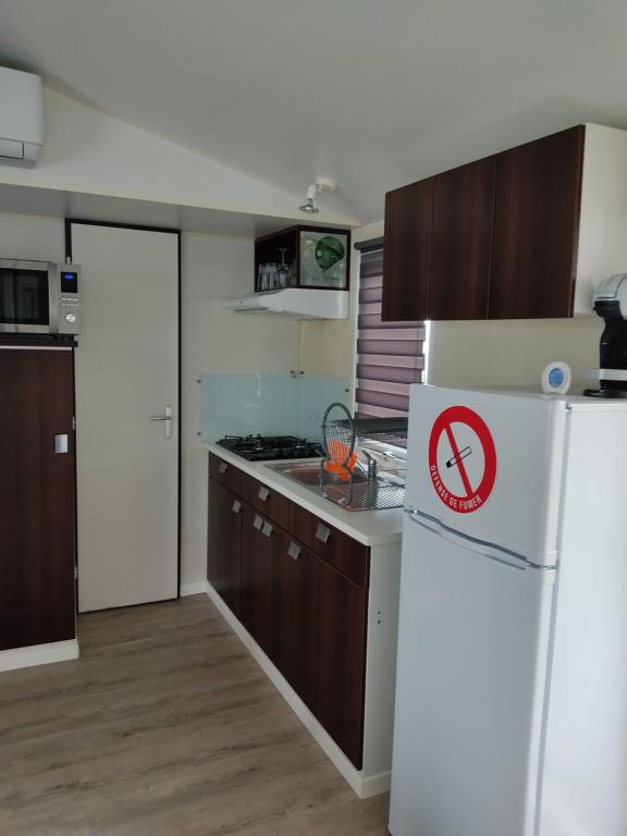 a kitchen with a white refrigerator with a sign on it at Camping du phare d opale p48 in Le Portel