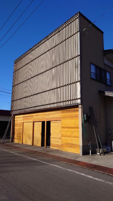 een gebouw met houten deuren aan de straatkant bij 白神山地の麓でヤギのいるゲストハウス　あわじ商店 in Fujisato