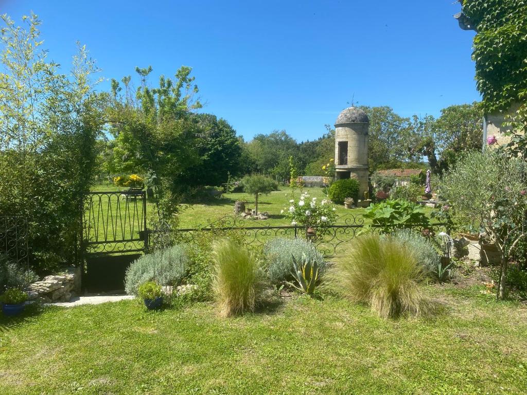 un jardin avec une porte et une tour en arrière-plan dans l'établissement Gîte l’aroma, à Faleyras