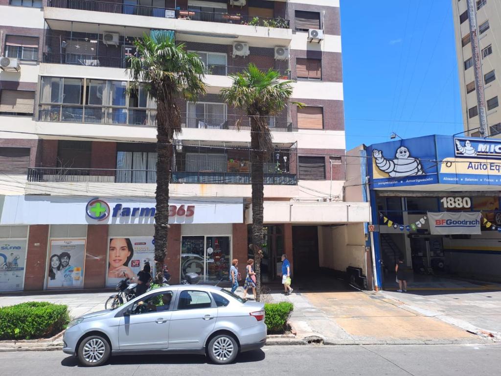 une voiture garée devant un immeuble avec des palmiers dans l'établissement Cómodo apartamento frente Quinta Presidencial, à Florida