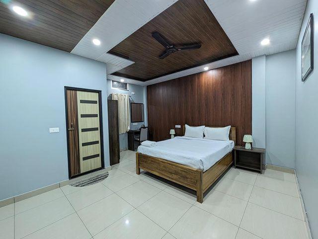 1 dormitorio con 1 cama y pared de madera en HOTEL ENCANTO IMPHAL, en Imphal