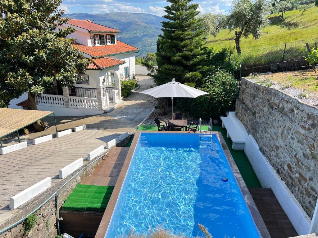 una piscina con sombrilla junto a una casa en Villa Samaritana - Casa da Vinha en Vila Marim