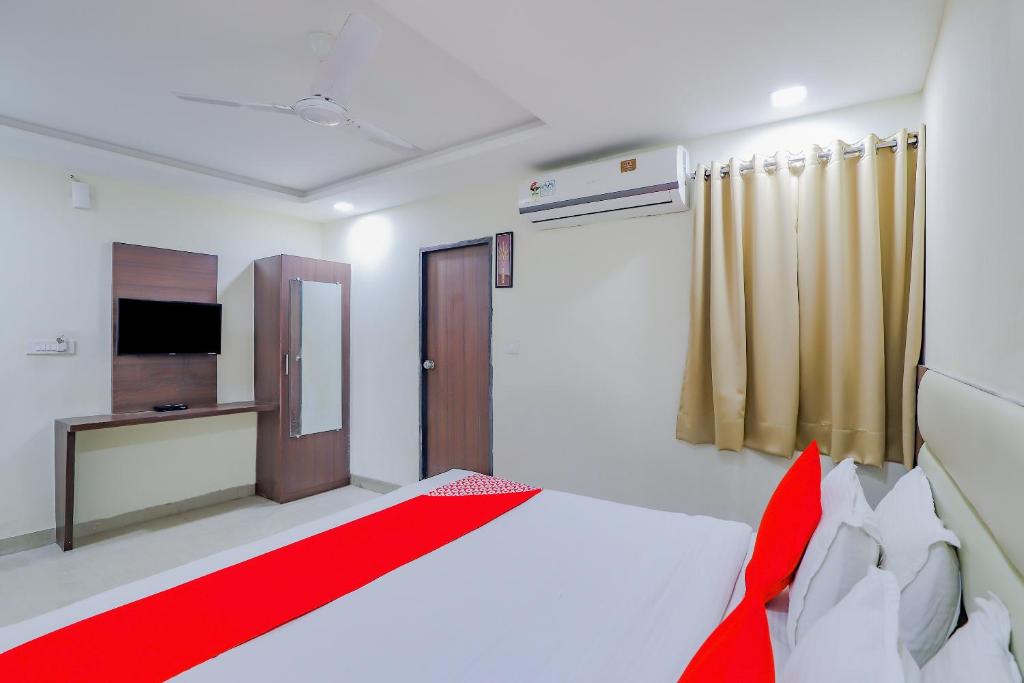 a bedroom with a bed with a red blanket and a television at Collection O Greenwood in Ahmedabad