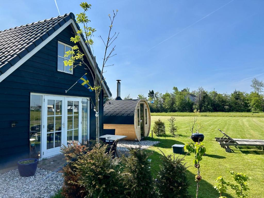 ein blaues Cottage mit einem Garten und einem Schuppen in der Unterkunft Vakantie in Duin- en Bollenstreek in Voorhout