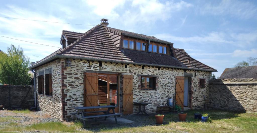 an old stone cottage with a bench in front of it at Gite de Tournieres in Tournières