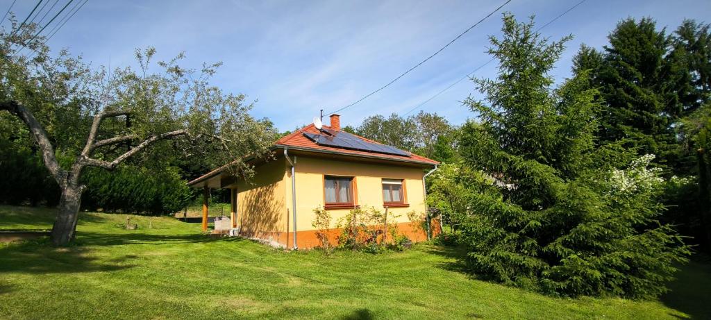 een geel huis met een rood dak in een tuin bij Mura Völgye Vendégház in Murarátka