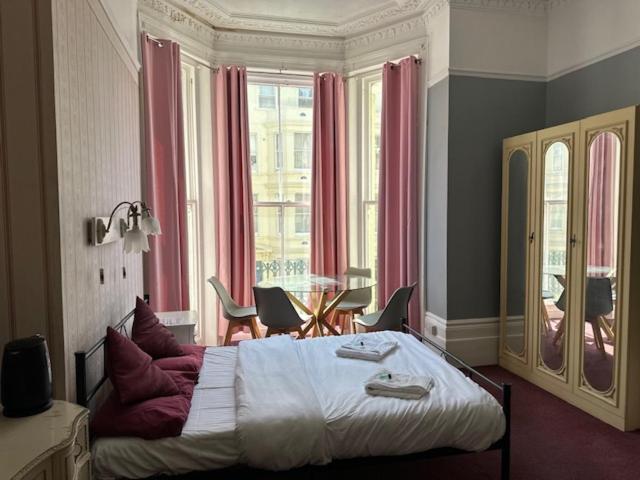 um quarto com uma cama grande, uma mesa e cadeiras em The Sherwood Guest House em Eastbourne