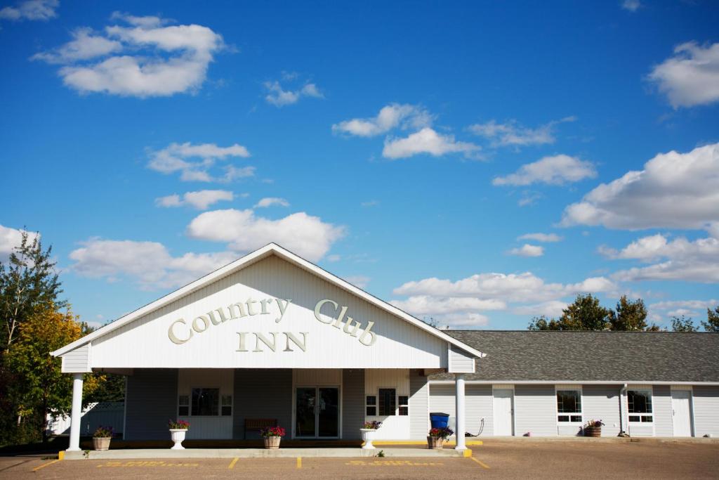 un edificio con un cartel de la posada del club de campo en Country Club Inn en Lacombe