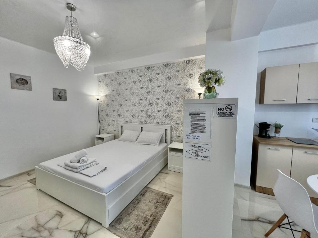 a white bedroom with a bed and a kitchen at ApartHotel Resort Sud B in Mamaia Sat/Năvodari