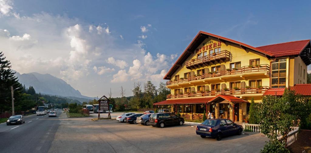 a large yellow building with cars parked next to a street at Hotel Riviera in Sinaia