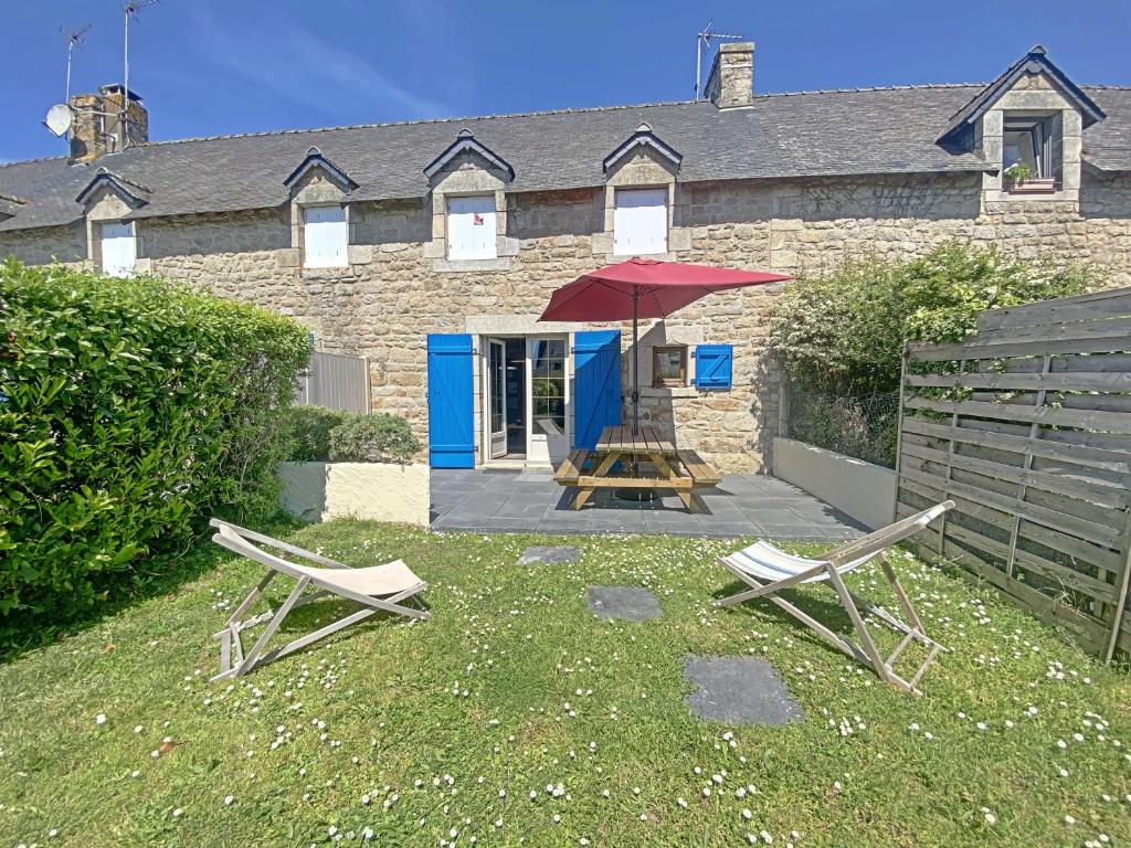 a house with two chairs and a table and an umbrella at RÉF 302 - LARMOR-PLAGE longère 3 pièces avec terrasse et jardin proche mer et commodités in Larmor-Plage