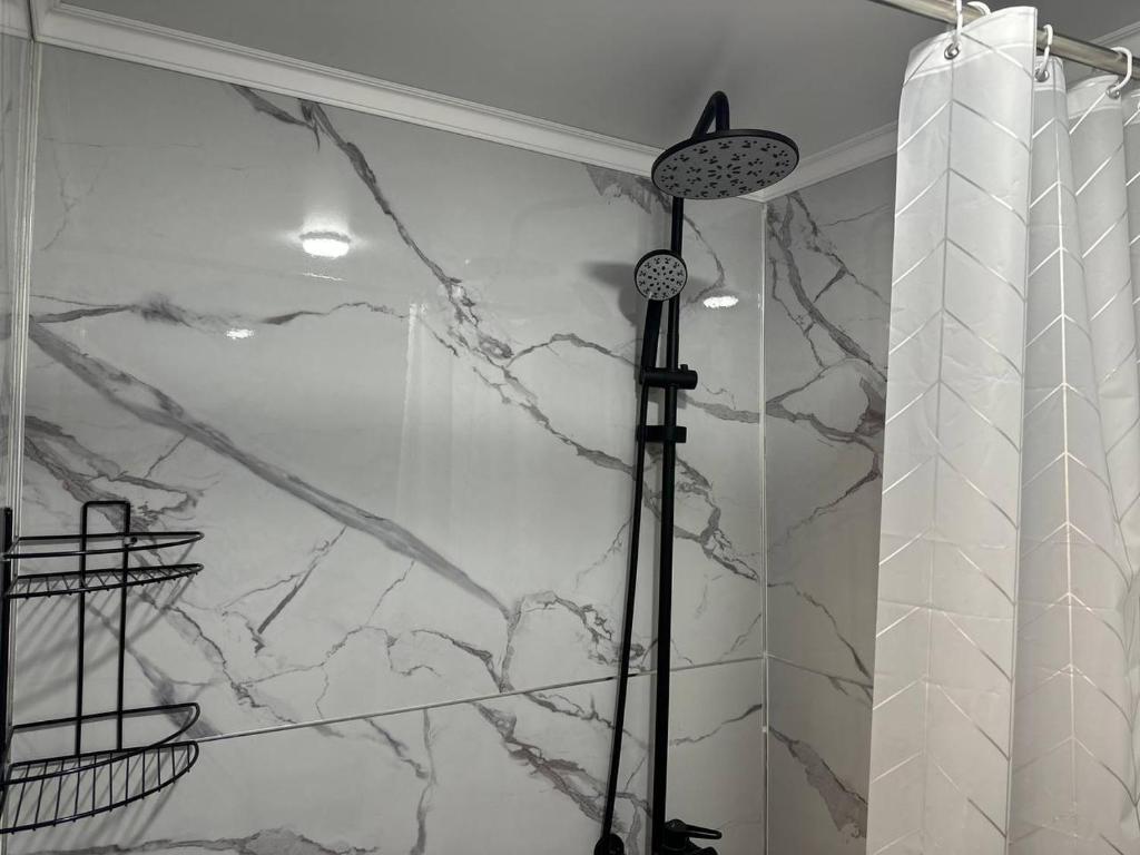 prysznic z czarno-białą marmurową ścianą w obiekcie Hostel Azamat w mieście Alamüdün