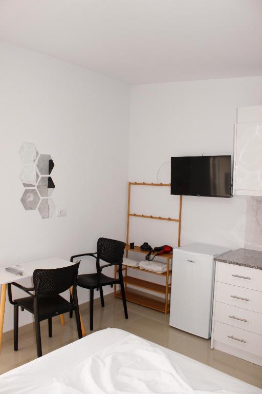 eine Küche mit 2 Stühlen, einem Tisch und einer Mikrowelle in der Unterkunft Andi's GuestHouse in Sarandë