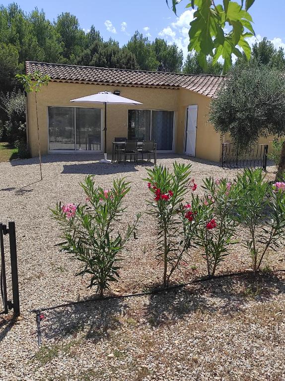 a building with a patio with an umbrella and some plants at Le temps d une escale in Lambesc