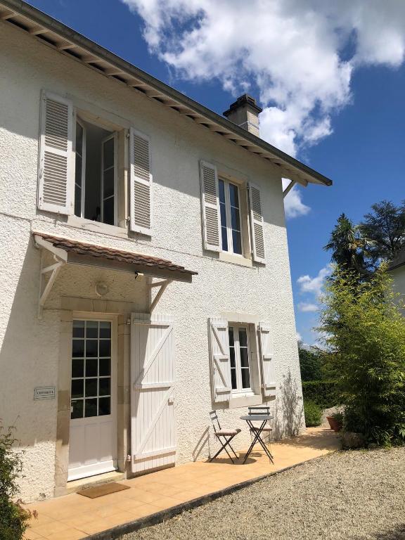 a white house with a chair in front of it at Le Petit Bourdieu - Chevreuil in Jurançon