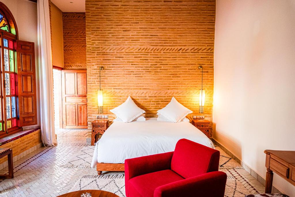 a bedroom with a bed and a red chair at Riad Al Ansari in Fez