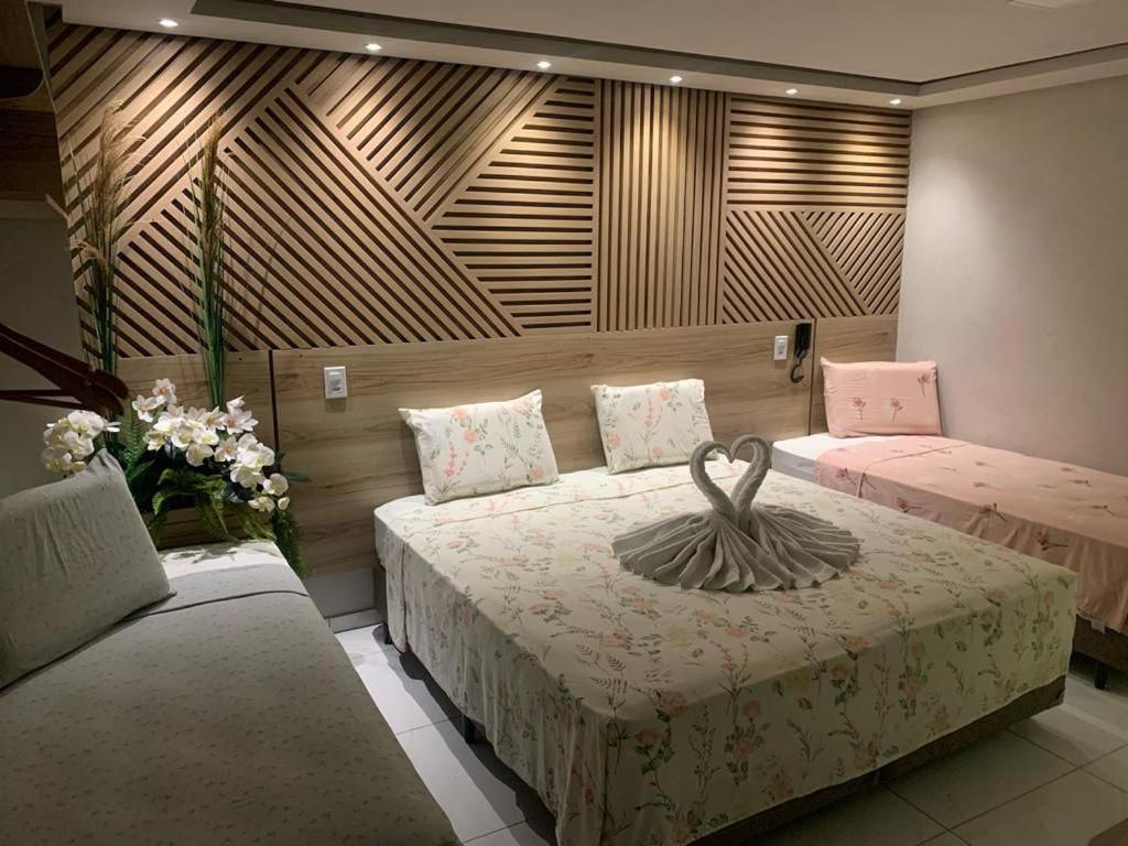 Un dormitorio con dos camas con una estatua de cisne. en Pousada Beija Flor en Maceió
