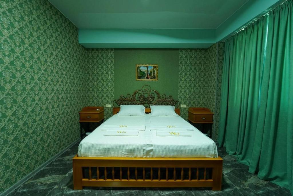 Schlafzimmer mit einem Bett mit grünen Wänden und grünen Vorhängen in der Unterkunft West Star Hotel in Kutaissi