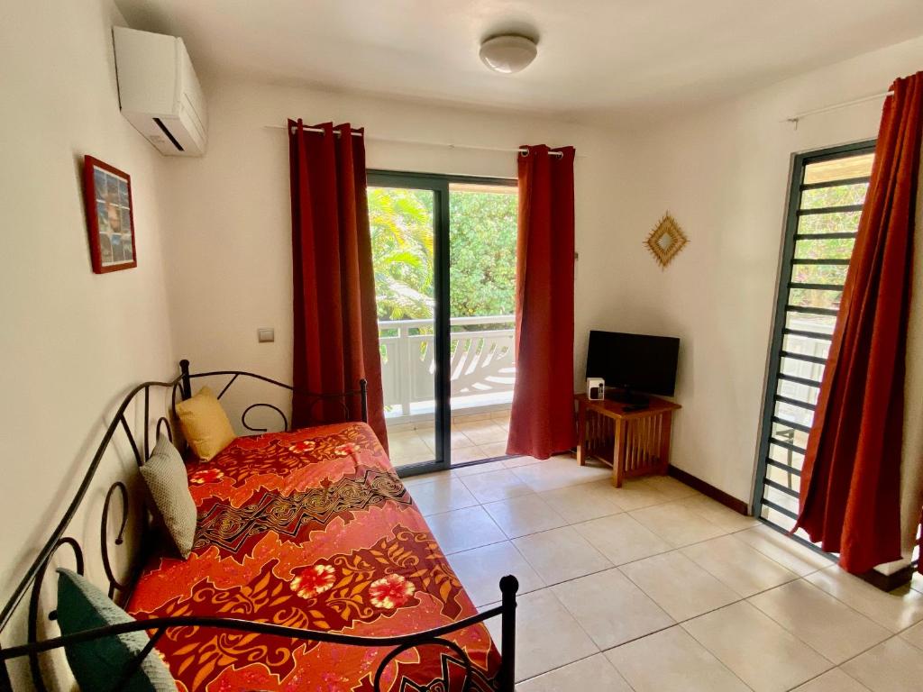 波拉波拉的住宿－Studio entre lagon et montagne，一间卧室配有红色窗帘的床和一个阳台
