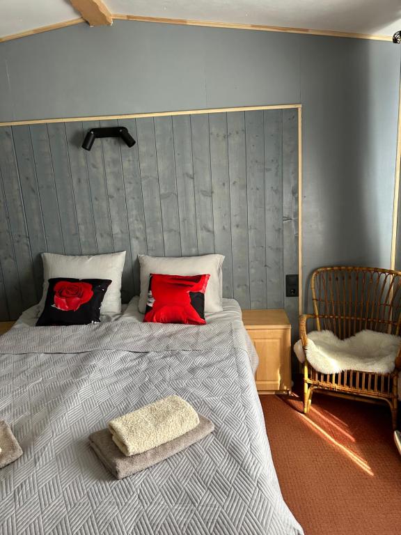 a bedroom with a bed with red pillows and a chair at Holiday Home Klavas in Sigulda