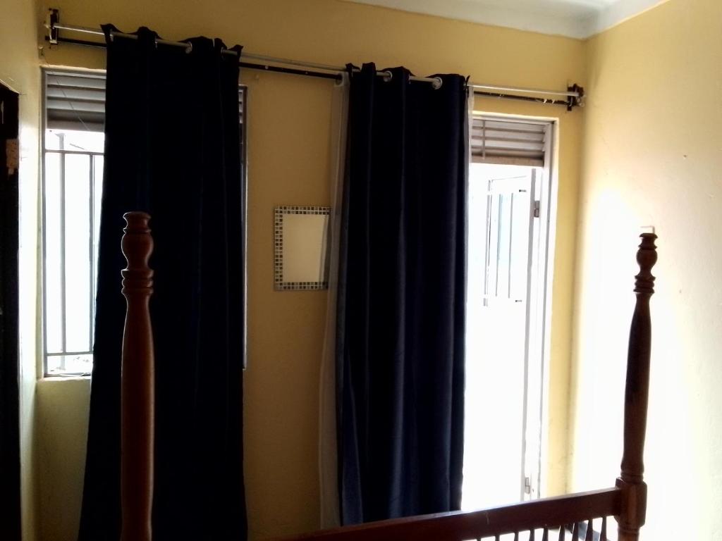 a bedroom with black curtains and a bed and a window at NIGHT ROCKS SUITS in Jinja