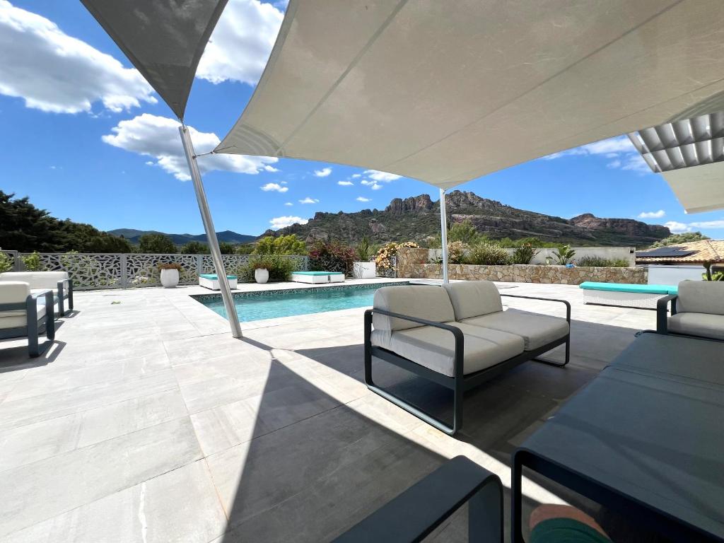 un patio avec des chaises et un parasol à côté d'une piscine dans l'établissement La belle vue, à Roquebrune-sur Argens