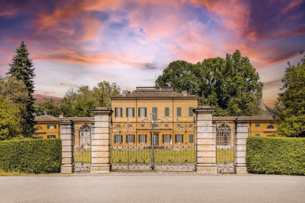 un grande edificio giallo con un cancello di fronte di Villa Vandelli - Nel cuore della Motor Valley a Modena