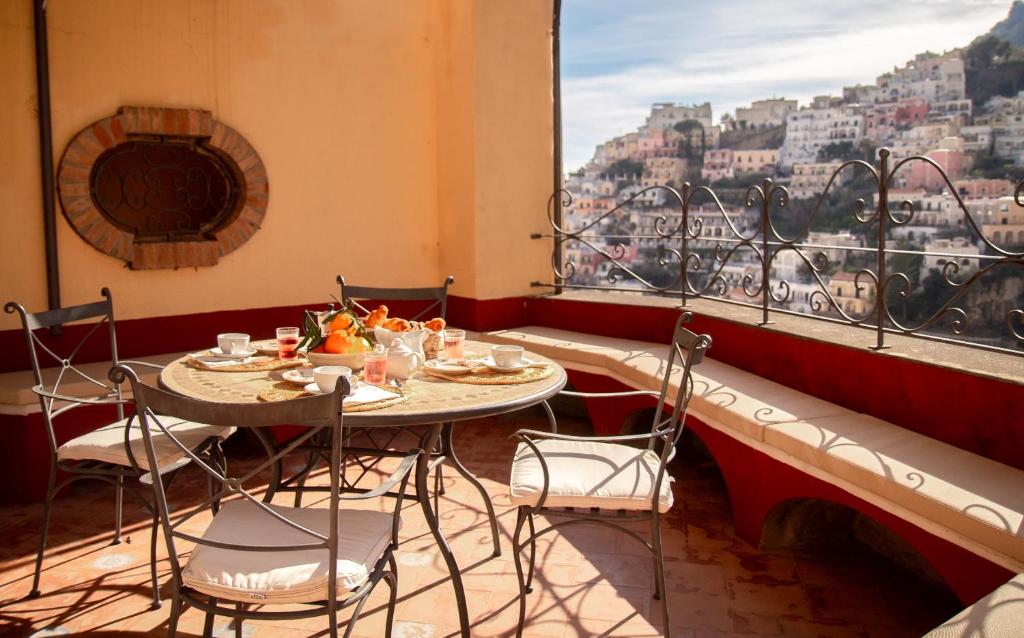 mesa y sillas en una habitación con ventana grande en Casa Giulia - sophisticated apartment with view, en Positano