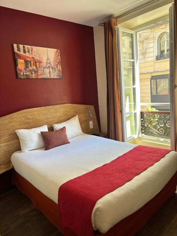 sypialnia z dużym łóżkiem i oknem w obiekcie Hotel Moulin Plaza w Paryżu