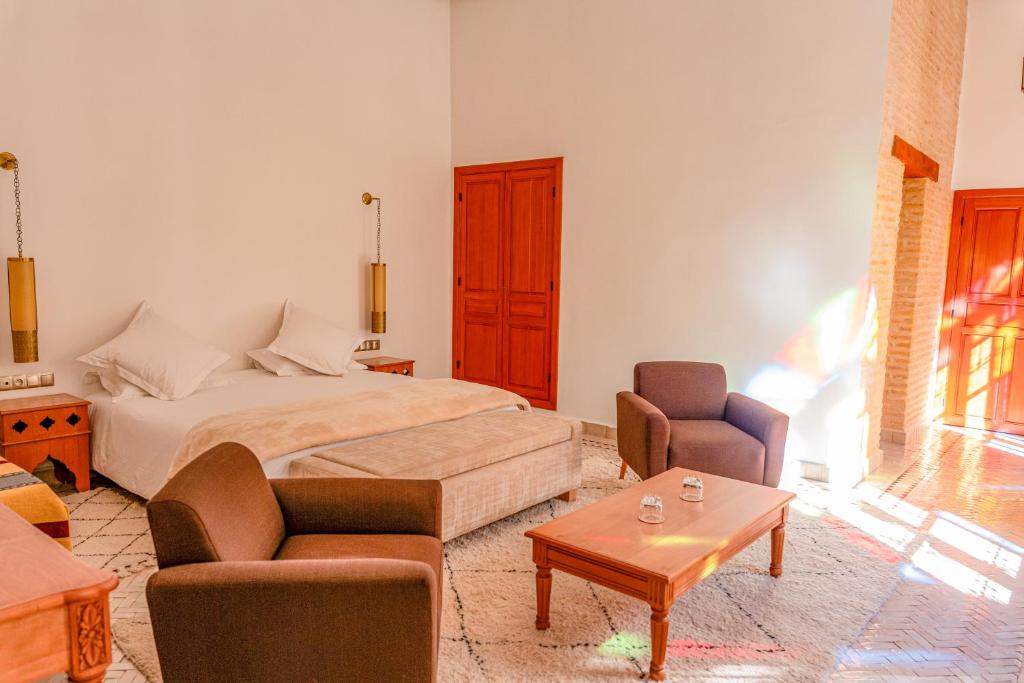 a bedroom with a bed and two chairs and a table at Riad Al Ansari in Fez