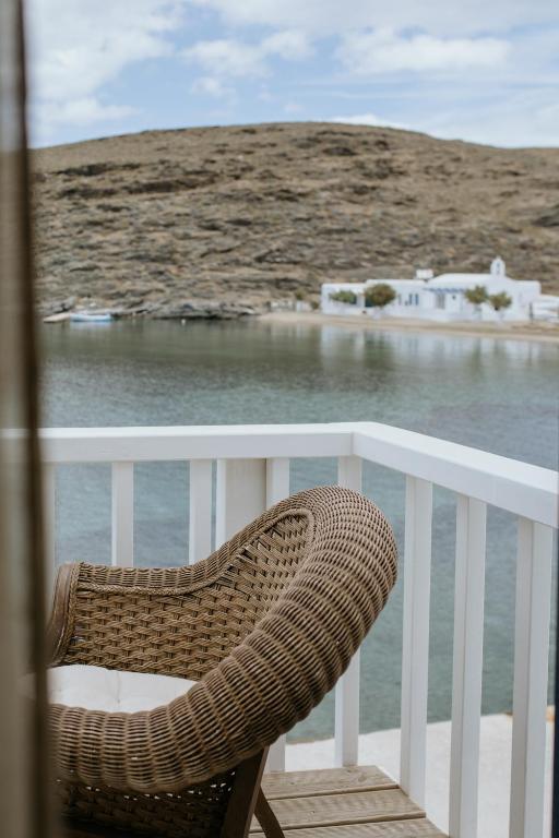 a wicker chair sitting on a balcony overlooking the water at Yi & Thalassa Living by KHI in Kithnos