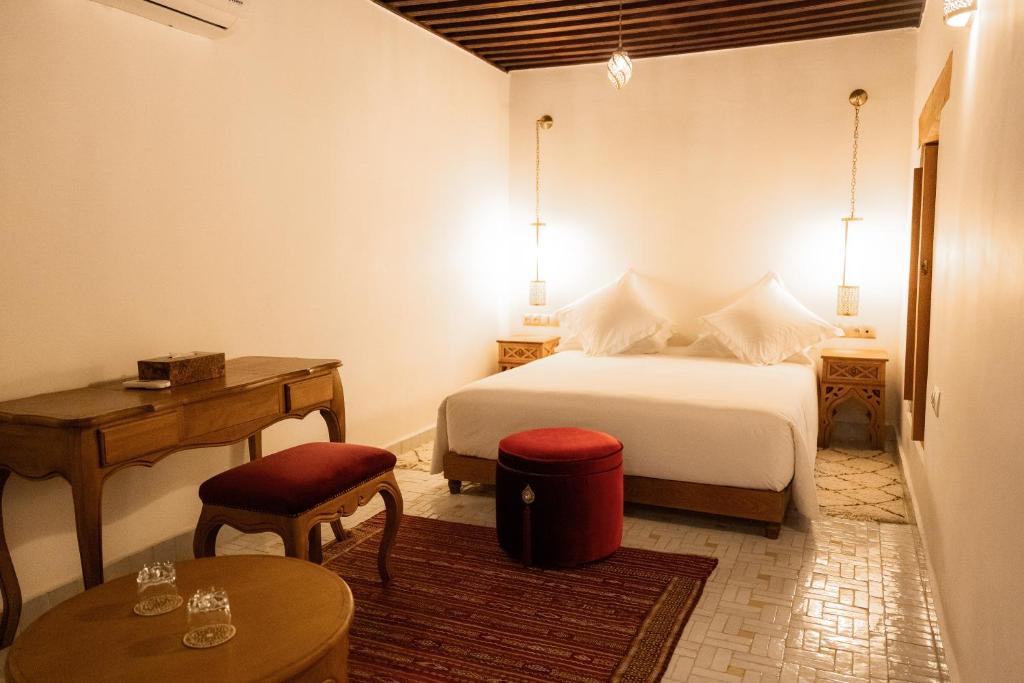 a bedroom with a bed and a table and a desk at Riad Al Ansari in Fez
