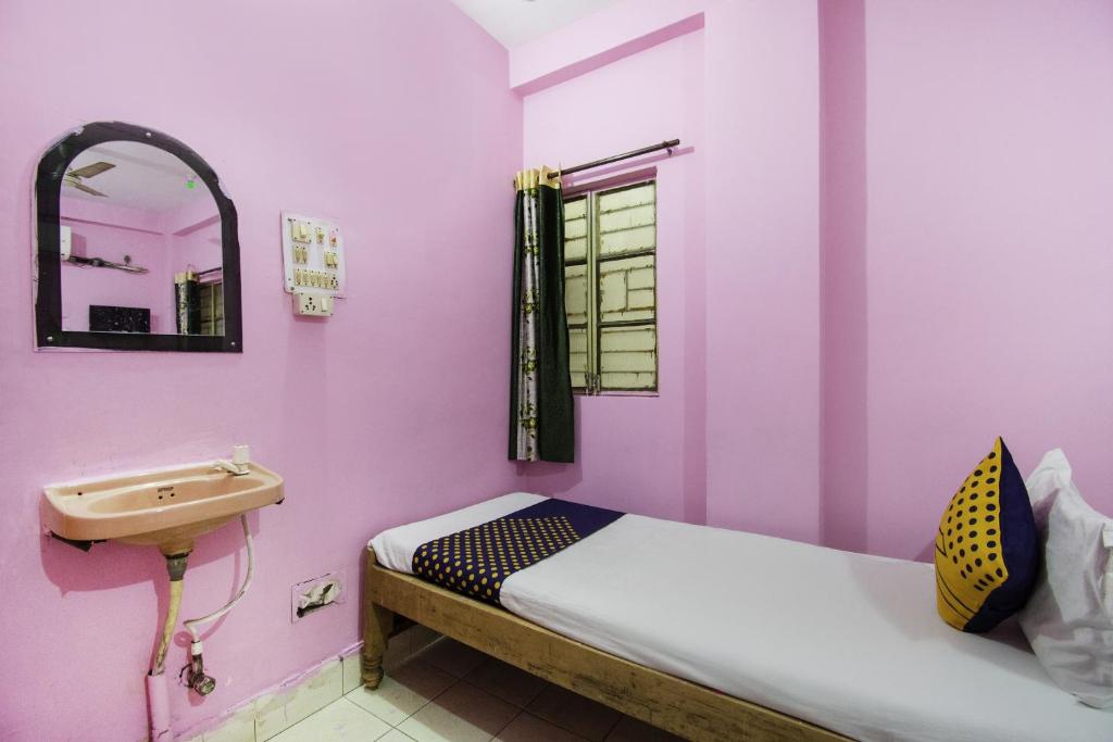 OYO Hotel Suvidha في جمشيدبور: غرفة صغيرة بها سرير ومغسلة