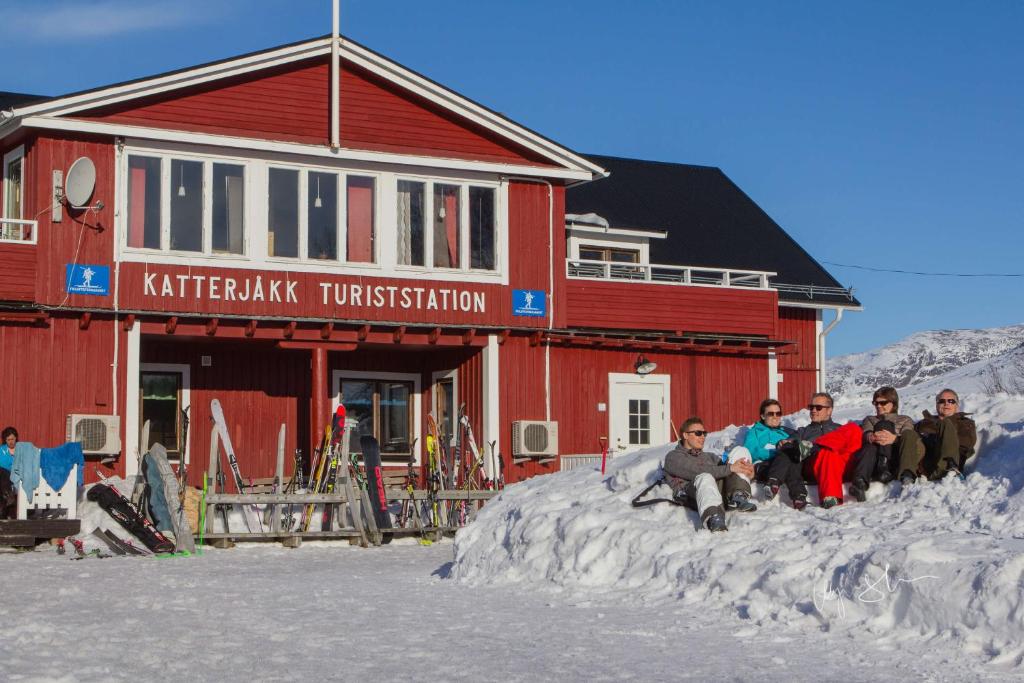 a group of people sitting in the snow in front of a building at Katterjokk Turiststation in Riksgränsen