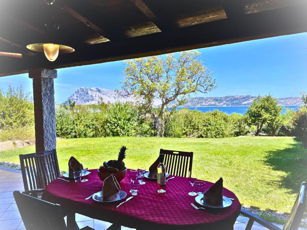 una mesa con un mantel púrpura en el patio en CAPO CODA CAVALLO VILLA SALINEDDA GIARDINO VISTA MARE, en Capo Coda Cavallo